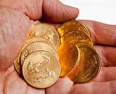 Hand holding gold coins.